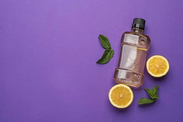 Mouthwash, fresh mint and lemon on purple background, flat lay. Space for text