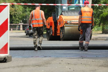 MYKOLAIV, UKRAINE - Ağustos 04, 2021: Yeni asfalt döşeyen yol onarım makineli işçiler