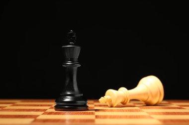 Siyah arkaplanda oyun taşları olan satranç tahtası