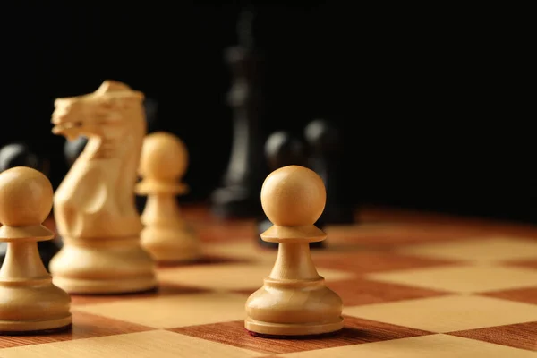 Chessboard with game pieces on black background