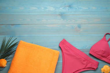 Plaj havlusu ve mayo açık mavi ahşap arka planda, düz yatıyordu. Metin için boşluk