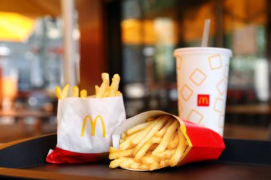 MYKOLAIV, UKRAINE - 11 Ağustos 2021: McDonald 's' ın büyük ve küçük porsiyonları kafeteryadaki tepside içkinin yanında.