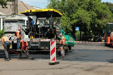 MYKOLAIV, UKRAINE - Ağustos 04, 2021: Yeni asfalt döşeyen yol onarım makineli işçiler