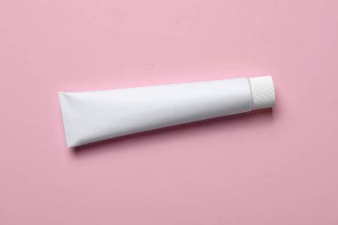 Pembe arka planda boş diş macunu tüpü, üst görünüm