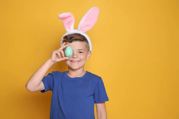 Roztomilý Chlapeček Zajíčkových Uších Drží Velikonoční Vajíčko Žlutém Pozadí Mezera — Stock fotografie