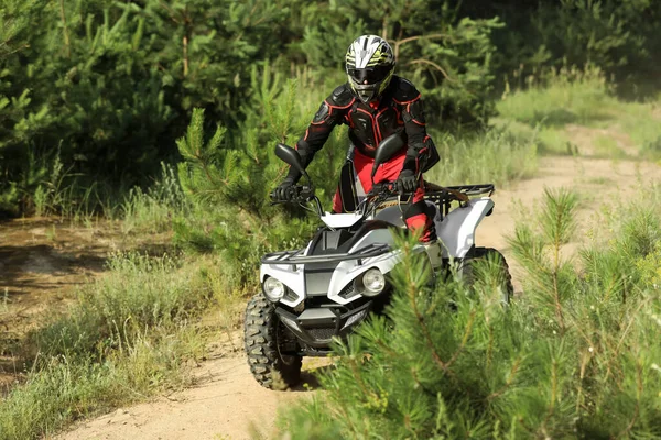 森の近くの砂の道で現代のクワッドバイクを運転する男 極端なスポーツ — ストック写真