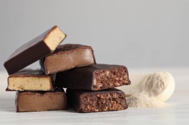 Lezzetli barlar ve beyaz masanın üzerinde protein tozu olan kaşıklar.