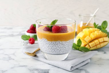 Mango soslu Chia pudingi ve beyaz mermer masada ahududu.