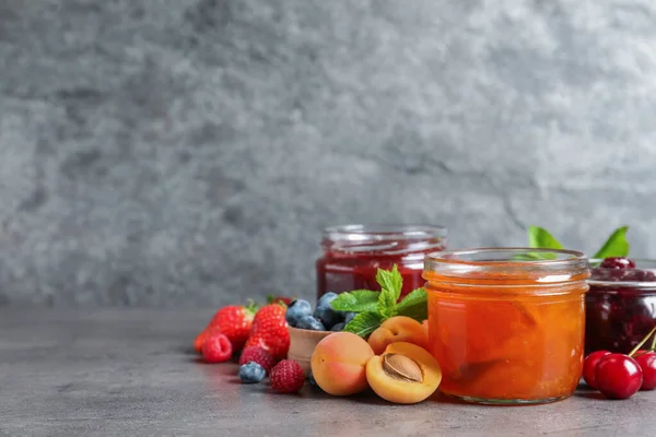 Frascos Con Diferentes Mermeladas Frutas Frescas Sobre Mesa Gris Espacio —  Fotos de Stock