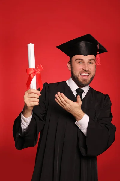 Gelukkige Student Met Afstudeerhoed Diploma Rode Achtergrond — Stockfoto