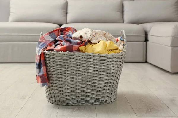 Wicker basket with dirty laundry on floor in living room