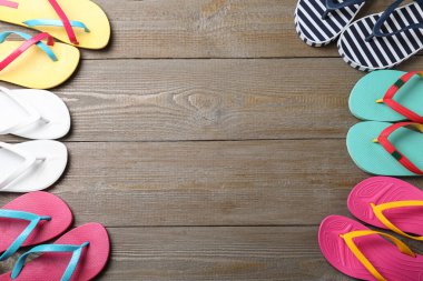 Tahta arka planda pek çok farklı parmak arası terlik, düz yatış. Metin için boşluk