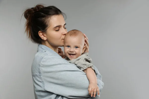 Hermosa Madre Besando Lindo Bebé Sobre Fondo Gris Espacio Para —  Fotos de Stock