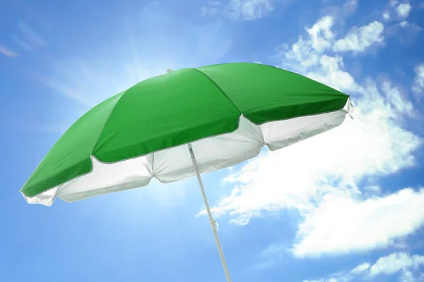 Open big green beach umbrella and beautiful blue sky with white clouds on background