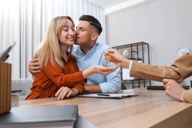 Emlakçı ofisteki çifte ev anahtarı veriyor.