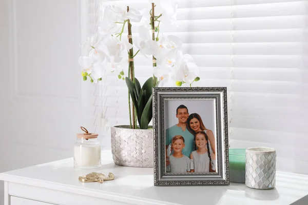 白いテーブルの上に額装された家族写真と蘭の花室内 — ストック写真