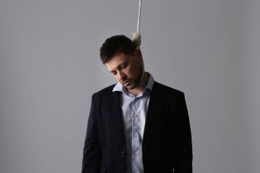 Kederli işadamı boynunda iple açık gri arka planda.