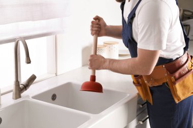 Tesisatçı lavabonun tıkanmasını açmak için lavabo pompası kullanıyor.