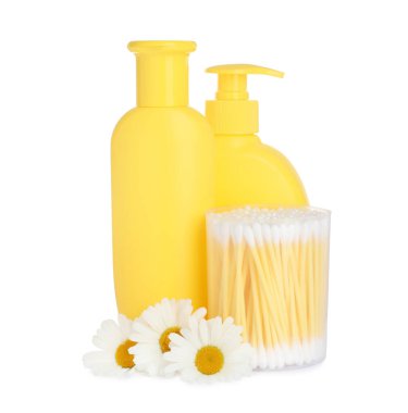 Bebek kozmetik ürünleri şişeleri, papatya çiçekleri ve beyaz arka planda pamuk örnekleri.