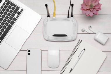 Yönlendirici, dizüstü bilgisayar ve ofis kırtasiyesi beyaz ahşap masa, düz yatıyordu