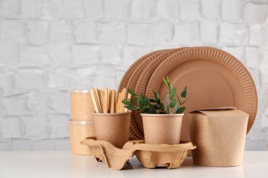 Tek kullanımlık çevre dostu ürünler beyaz ahşap masada.