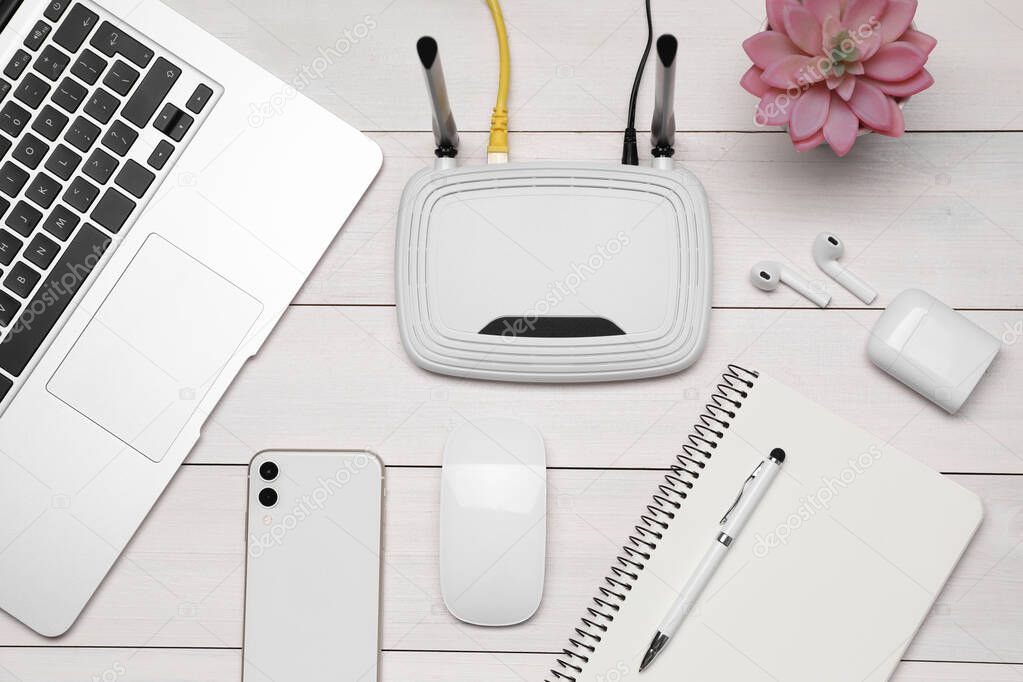 Composition with router, laptop and office stationery on white wooden table, flat lay