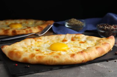 Gri masada peynirli ve yumurtalı taze ev yapımı khachapuri, yakın plan.