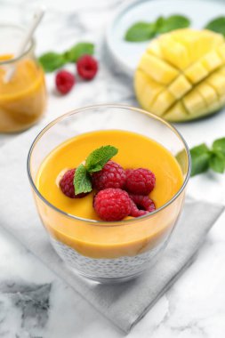 Mango soslu Chia pudingi ve beyaz mermer masada ahududu.