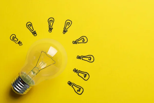 Many Drawn Lightbulbs Real One Yellow Background Top View Space — Stock Photo, Image