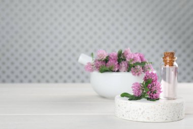 Güzel yonca çiçekleri ve beyaz ahşap masada gerekli yağ şişesi. Metin için boşluk