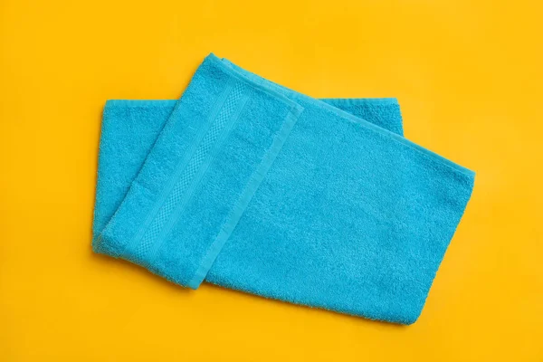黄色の背景に薄い青のビーチタオルを折り トップビュー — ストック写真