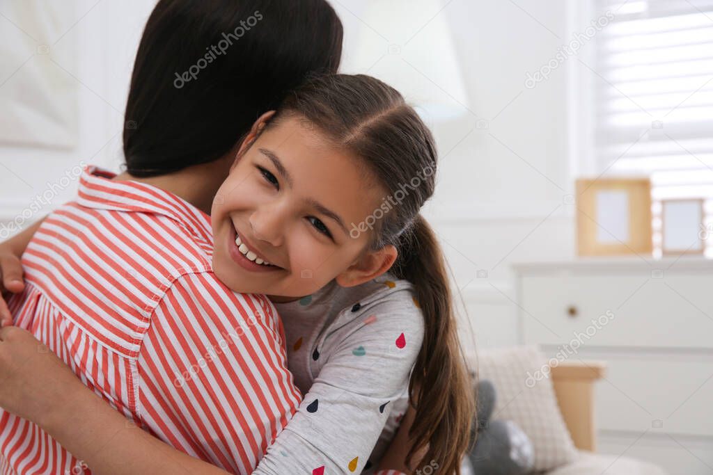Cute little girl hugging her mother in living room. Adoption concept