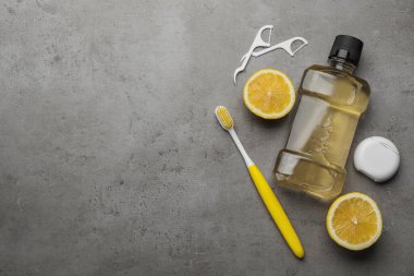 Ağız gargarası ve diğer ağız temizliği ürünleriyle birlikte gri masanın üzerinde düz bir kompozisyon vardı. Metin için boşluk