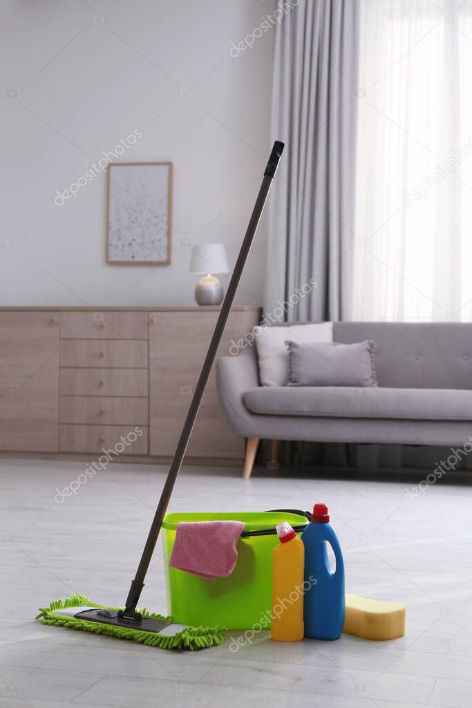 Bucket, cleaning products and mop on floor in living room