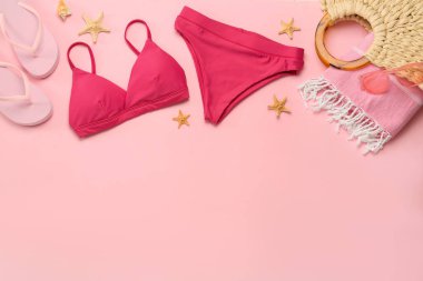 Pembe arka planda şık bikini ve plaj aksesuarları, düz yatış. Metin için boşluk