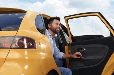 Dışarıda taksiden inen yakışıklı genç adam.