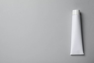 Açık gri arka planda boş diş macunu tüpü, üst manzara. Metin için boşluk