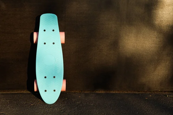 Moderne Lichtblauwe Skateboard Met Roze Wielen Buurt Van Zwarte Muur — Stockfoto