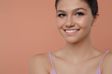 Soluk mercan arka planda güzel bir kız, mesaj için yer var. Güzel bir yüz, pürüzsüz bir ten.