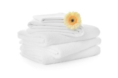 Beyaz arka planda Gerbera olan havlu ve çarşaf yığını
