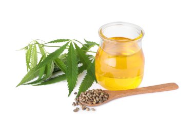 Kenevir yağı kavanozu, beyaz arka planda taze yapraklar ve tohumlar.