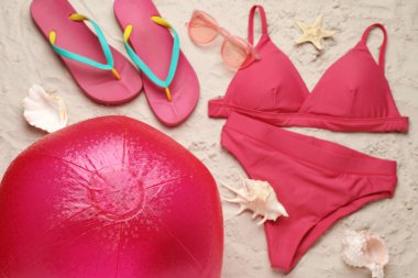 Parlak plaj topu ve diğer aksesuarlar kum üzerinde, düz yatıyordu.