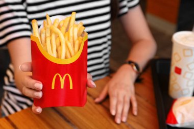 MYKOLAIV, UKRAINE - 11 Ağustos 2021: McDonald 's patates kızartmalı ve kafedeki masada içen kadın, yakın plan