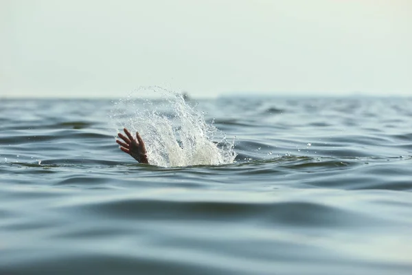 Drowning woman reaching for help in sea