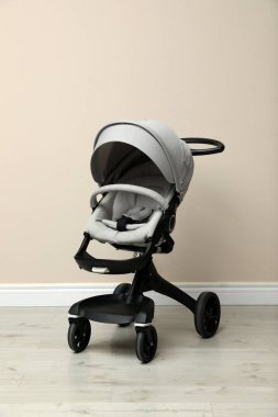 Bebek arabası. Bej duvarın yanında modern bebek arabası