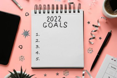 Not defterinde 2022 hedef ve pembe zemin üzerinde farklı nesneler yazıyor. Yeni Yıl Hedefleri
