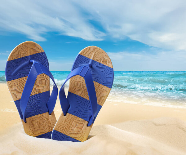 Striped flip flops on sandy beach near sea