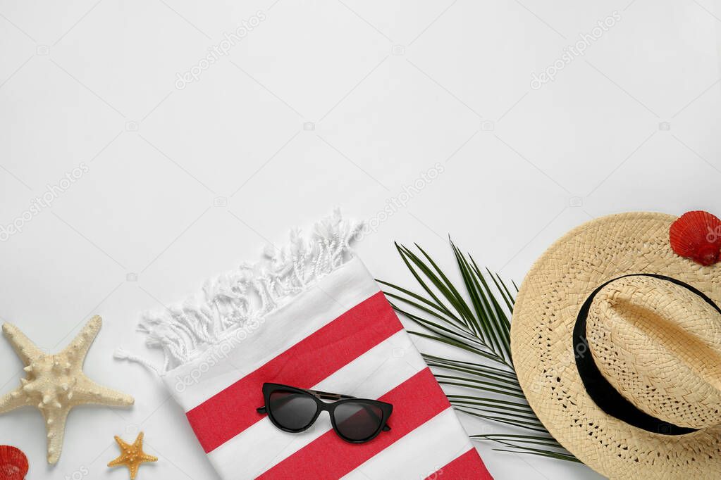 Beach towel, straw hat and sunglasses on light background, flat lay. Space for text