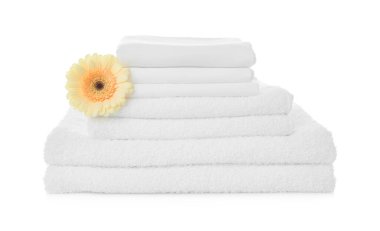 Beyaz arka planda Gerbera olan havlu ve çarşaf yığını