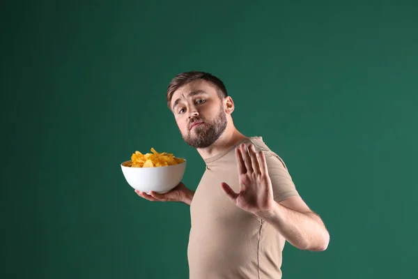 Greedy Young Man Hiding Bowl Chips Green Background — Stock Photo, Image